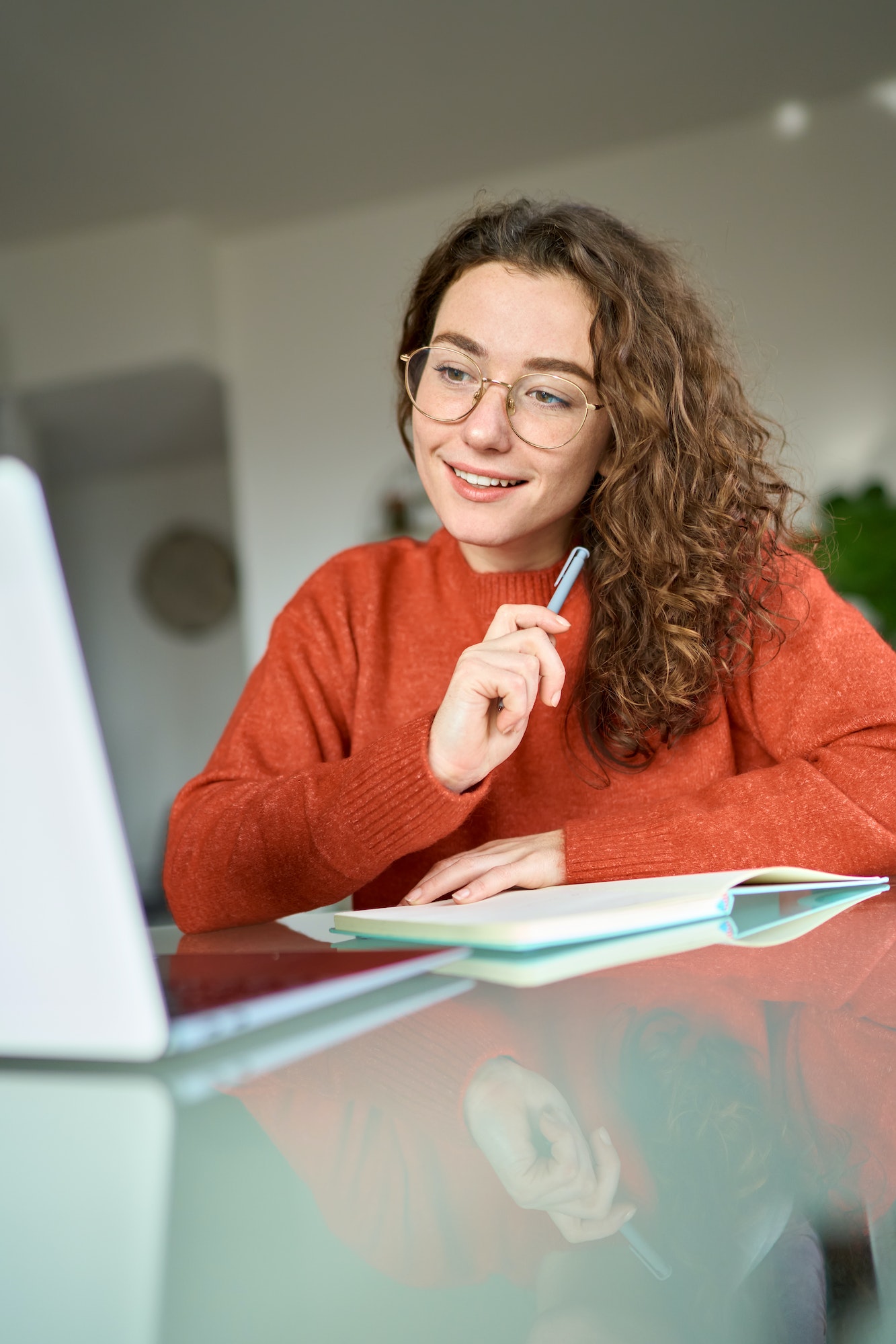Young woman student using laptop looking at computer elearning at home.